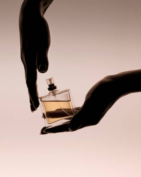 istock Hands hold a perfume bottle with golden liquid, on a beige background. 2152320361
