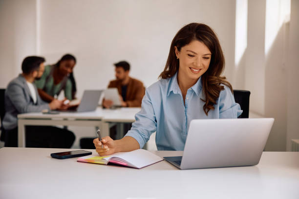 istock Happy businesswoman taking notes while working on laptop in modern office. 2152322214