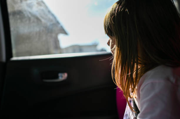 Preschool girl looking throw window during car trip.