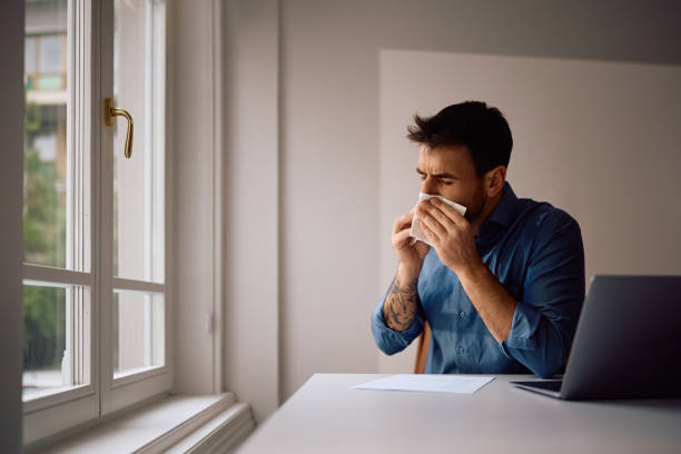 istock Sick businessman blowing nose while working on laptop in the office. 2152322491