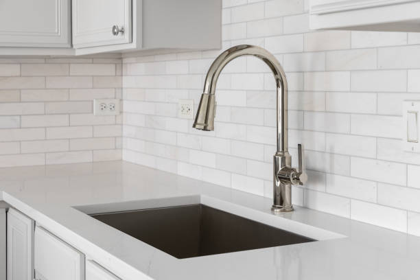 istock A kitchen sink detail with white cabinets and a marble subway tile backsplash. 2152324961