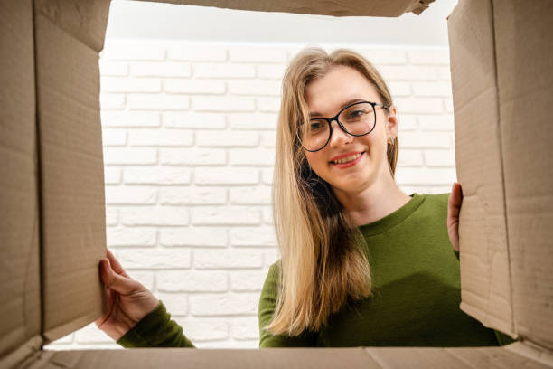 istock Happy female client opening a carton box and looking inside. Delivering parcel, unpacking. 2152327043