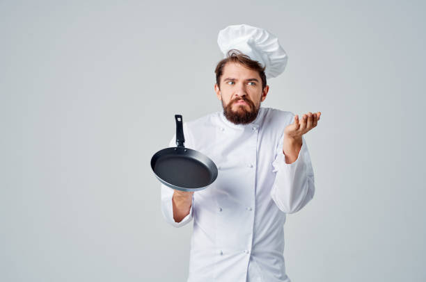 istock a man in a chef's uniform with a frying pan in hand Professional 2152330524