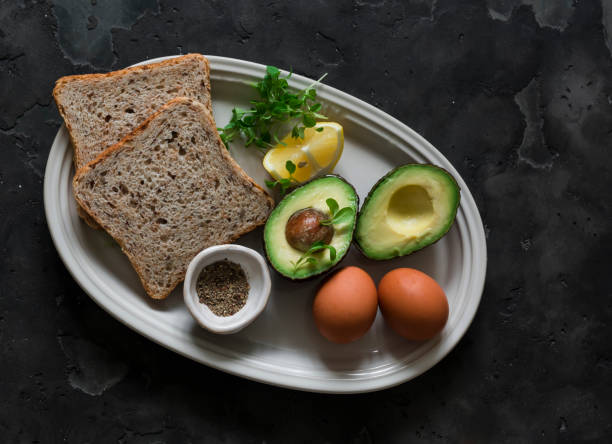 istock Ingredients for making whole-grain toast with avocado, scrambled eggs and microgreens on a dark background, top view 2152334415