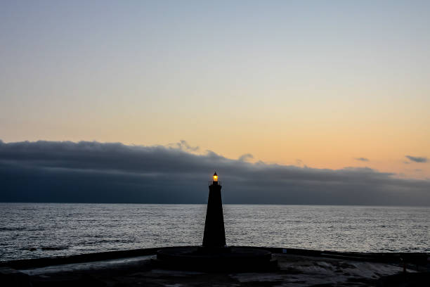 istock A lighthouse is lit up in the ocean at sunset 2152337306