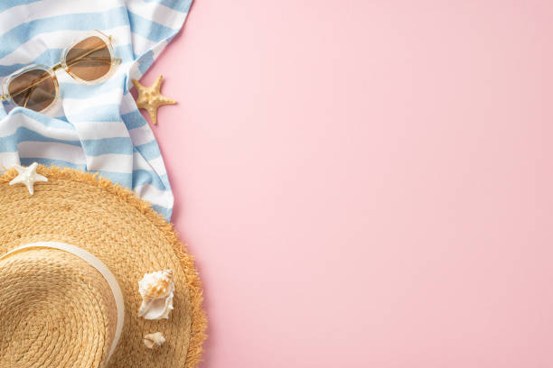 istock A stylized summer setting featuring a straw hat, sunglasses, and a striped towel with starfish, arranged on a vibrant pink background. Perfect for vacation and beach themes 2152338299