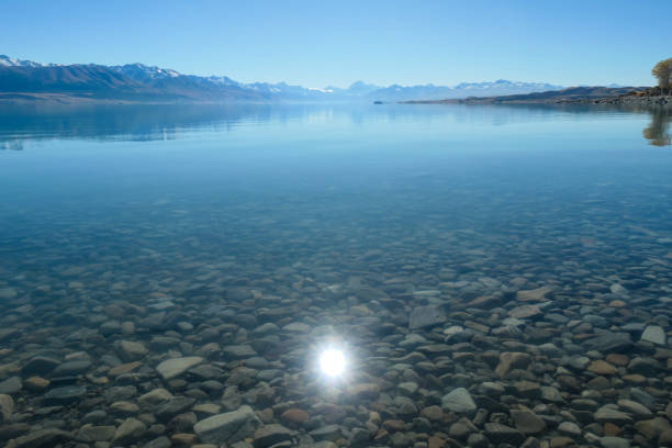 The sun reflects off the shallows of Lake Pukaki in the Southern Alps of the South Island.  In the far distance is Aoraki Mount Cook.  This image was taken on a sunny and cold afternoon on 29 April 2024.