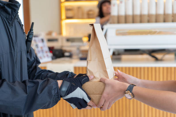 Two hands passing paper shopping bags.