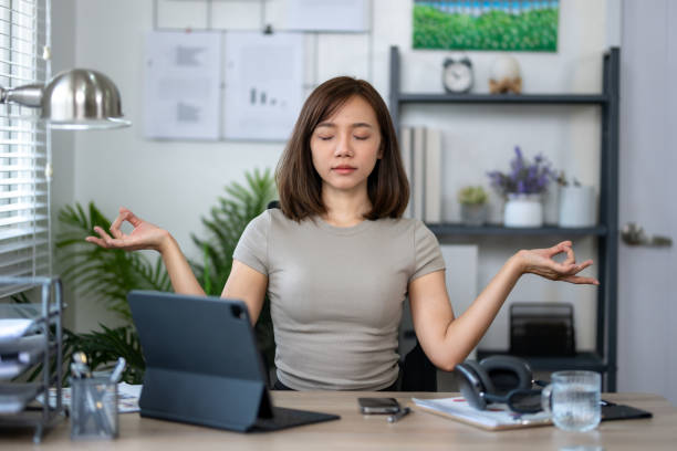 istock A woman is sitting at a desk with a tablet and a computer. She is practicing yoga and she is in a calm and focused state 2152351021