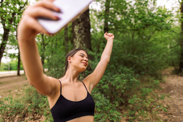 Young sport woman wearing sport clothes preparing for running in nature and taking selfies.