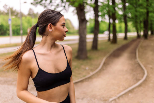 Young sport woman wearing sport clothes and running in a park in spring.