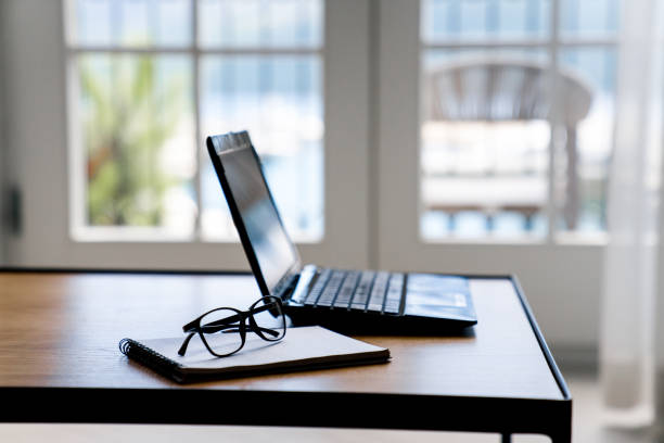 istock Working from home. Workplace with laptop and spectacles on summer vacation. Remote office in cozy living room with big window, balcony and sea view. Concept of freelance, online business, workation 2152356659