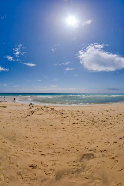 istock A beach with a clear blue sky and a few people walking on the sand 2152358982