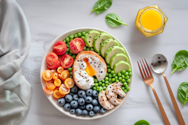 Buddha bowl with avocado, egg, chickpeas, tomato, cucumber, spinach and blueberries