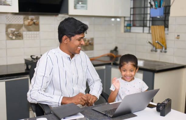 istock indian father and her daughter using laptop computer in the kitchen at home 2152363077