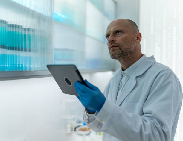 istock Confident male scientist in lab coat at a laboratory. Checking research notes on a tablet 2152363904