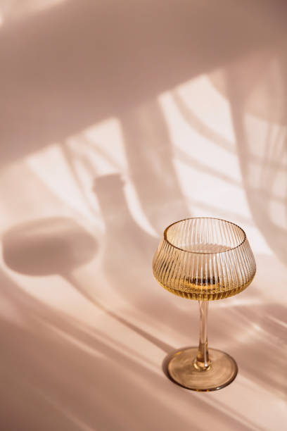 istock Two glasses with white wine placed on light beige background with shadows 2152369090