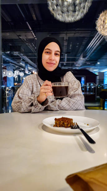 istock female drinking coffee with beautiful reflections on window behind him with desserts plate 2152374746