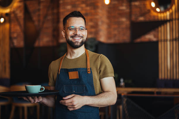 istock Young waiter serving coffee in a cafe 2152377323