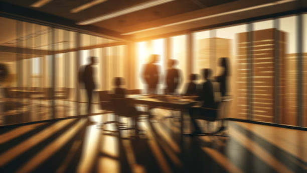 Back view of two business people standing in the office and looking through window. Copy space.