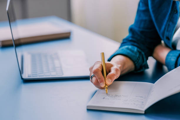 istock Focused Young Professional Writing in Notebook at Desk 2152391668
