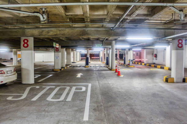 istock empty paid underground car parking, concrete poles artificial cool neon lights, barrier entrance, standard bay size 2152394941