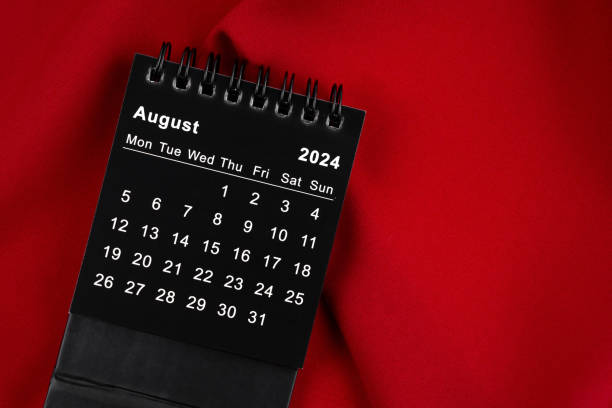 istock August 2024 Black spiral desktop calendar on red fabric. 2152406010