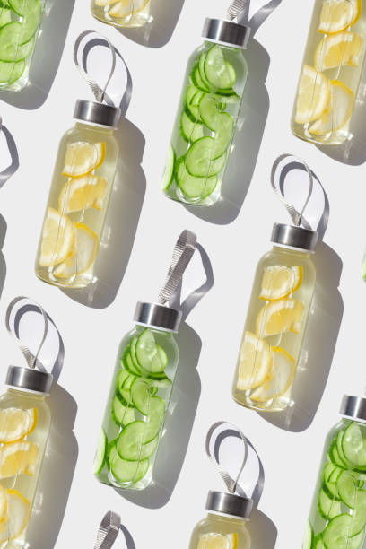 istock Cleansing, refreshing Lemon, cucumber water drink detox, shadow at sunlight on white, sun glare. Wellness, alkaline diet, eating healthy concept. glass reusable water bottle, top view pattern 2152407669