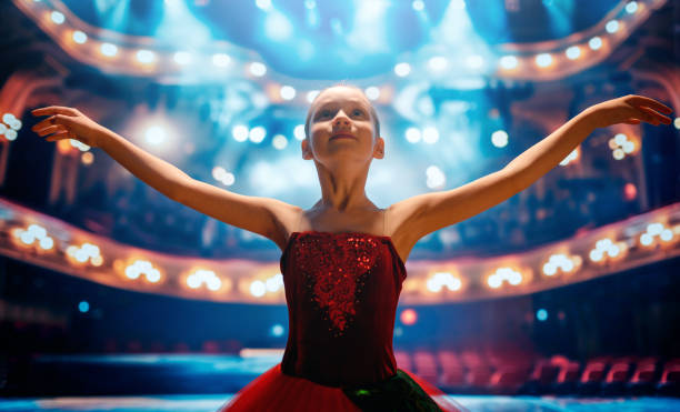 Cute little girl dreaming of becoming a ballerina. Child girl in a red tutu dancing on the stage.