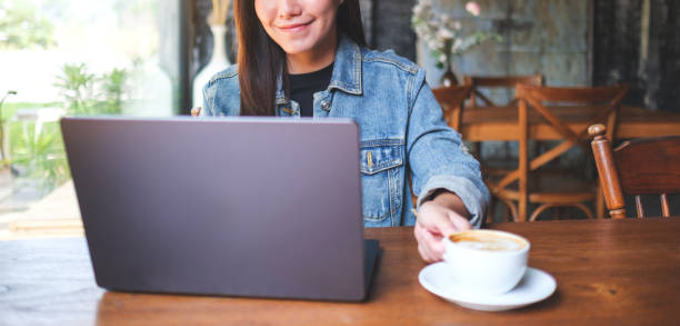 istock Closeup image of a young woman drinking coffee while working on laptop computer in cafe 2152418339