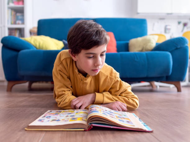 istock Young Child Engrossed in Reading a Colorful Book on Floor 2152424370