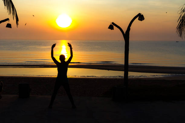 silhouette of a man with hands raised up on the beach and sunset in the background. High quality photo