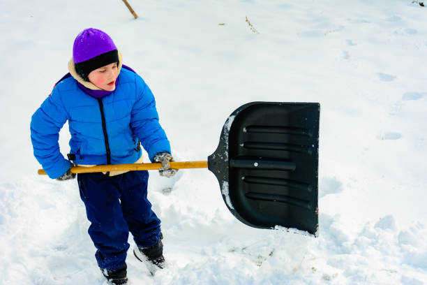 istock Smiling boy is carrying snow on a shovel, Child cleans the yard after a snowfall. 2152425996