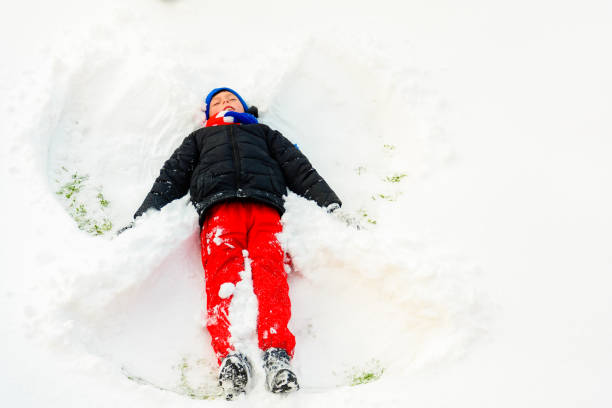 istock A boy in white fluffy snow makes an angel. 2152426162