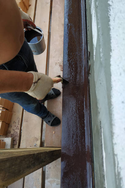 istock A man paints a metal corner with brown paint, working on a construction site. 2152426367