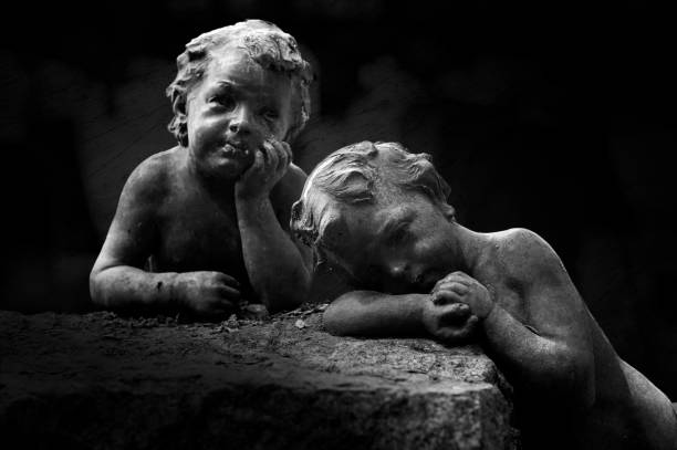 Vintage image of a sad angel on a cemetery against the background of leaves (details)