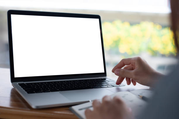 Mockup blank screen laptop computer. Business woman using and typing on laptop with blank white screen on wooden table in modern loft cafe, web template design for online marketing