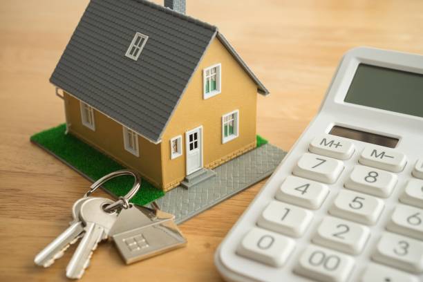 istock House model, key and white calculator on wooden table background. 2152455378