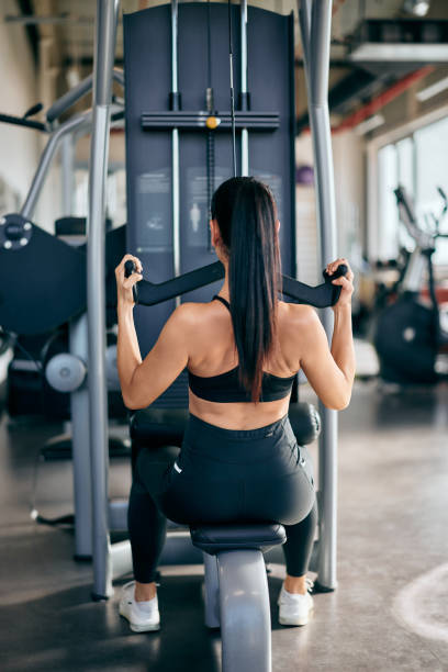 istock Photo of girls back, doing an exercise for back, lat pull down machine, at the gym. 2152458485