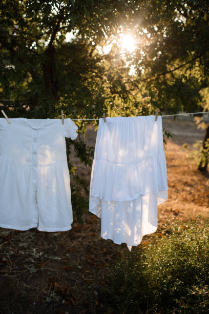 White dresses hanging on rope with pins outdoor close up.