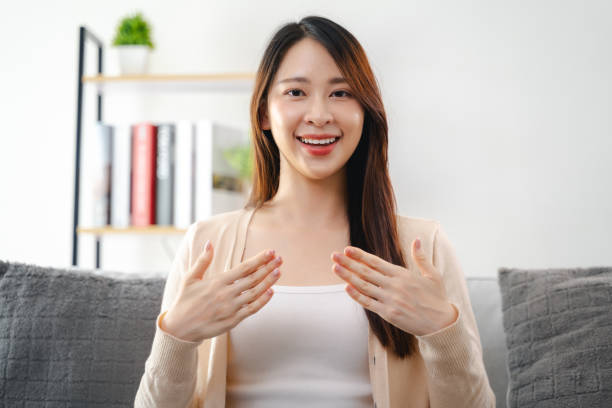 istock A young deaf woman is sitting on a couch and making a sign Language to communicate. 2152475462
