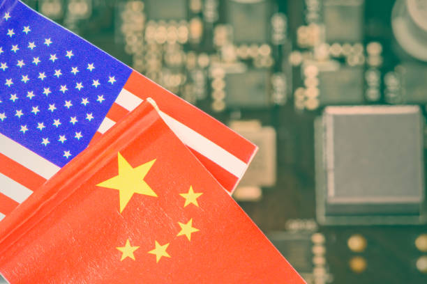 istock Flags of USA and China fly over a motherboard containing a processor, CPU chip. A semiconductor war erupted between two major countries, with the US prohibiting sophisticated AI chip exports to China. 2152485805