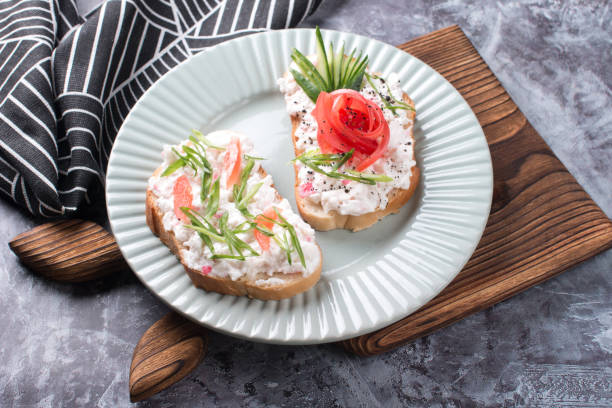 istock Bruschetta, a slice of bread with cheese paste, tomato and cucumber. Beautifully decorated sandwiches on a plate 2152490741