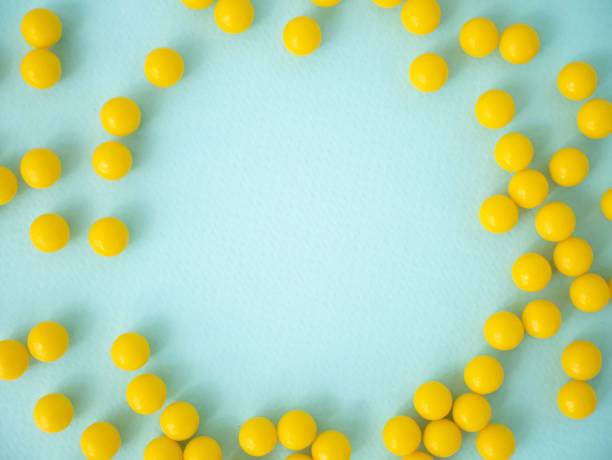 Round yellow tablets or dietary supplements are scattered on a blue background with space for text. A layout for a pharmacy, advertising medicines. View from above