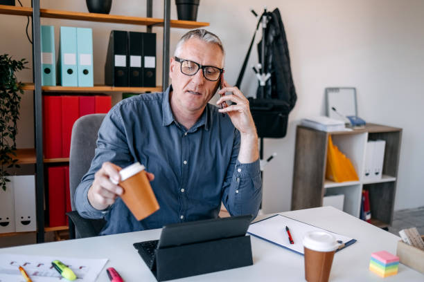istock Man working overtime using laptop and talking on mobile phone 2152508214