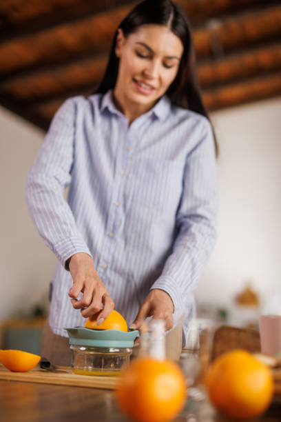 istock Woman squeezing fresh orange juice at her dining table 2152517749