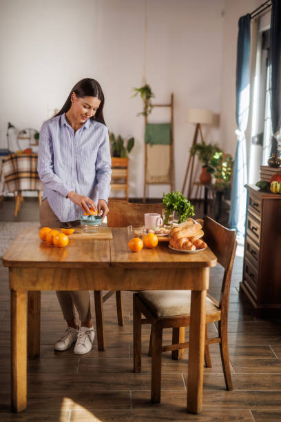 istock Woman squeezing fresh orange juice at her dining table 2152517770