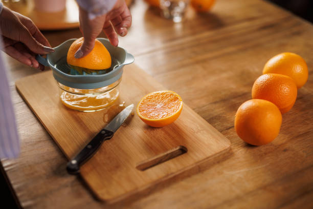istock Woman squeezing fresh orange juice at her dining table 2152517796