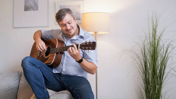 istock Musical hobby guitar skill man playing sofa home 2152517825