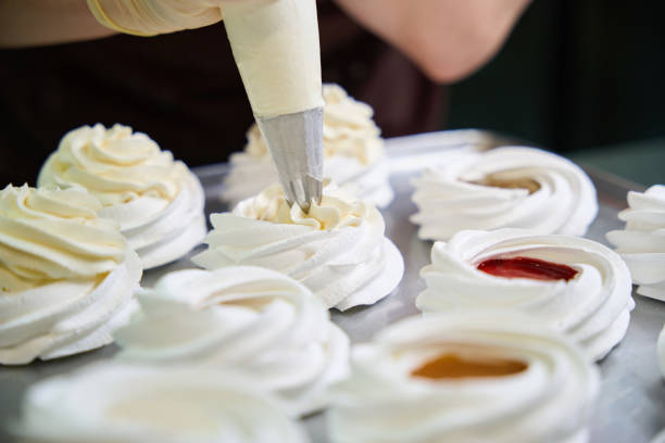 istock Confectioner squeezing whipped cheese cream from pastry bag at merengue nest 2152524956